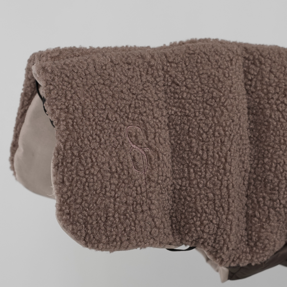 Zbliżenie na wytłoczony monogram Staey na płaszczu dla psa w kolorze Taupe