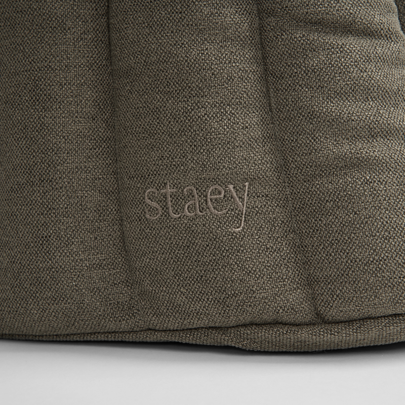 Close-up of the embossed Staey wordmark on the olive teddy carrier bag